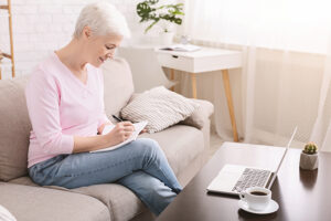 woman conducting research and jotting down notes to ask on her assisted living community tour